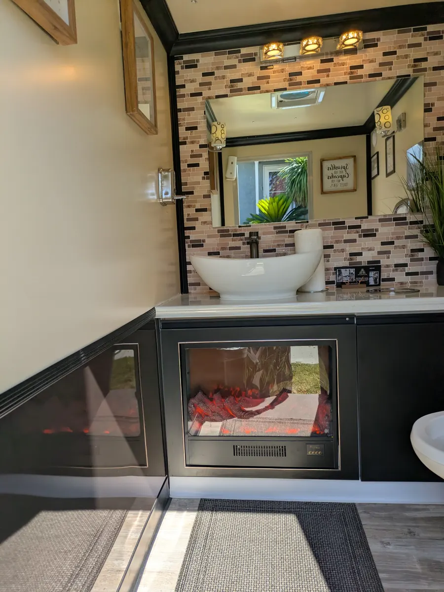 Inside the Deluxe Flush trailer: vessel sink vanity, mosaic tile, warm lighting, and an electric fireplace